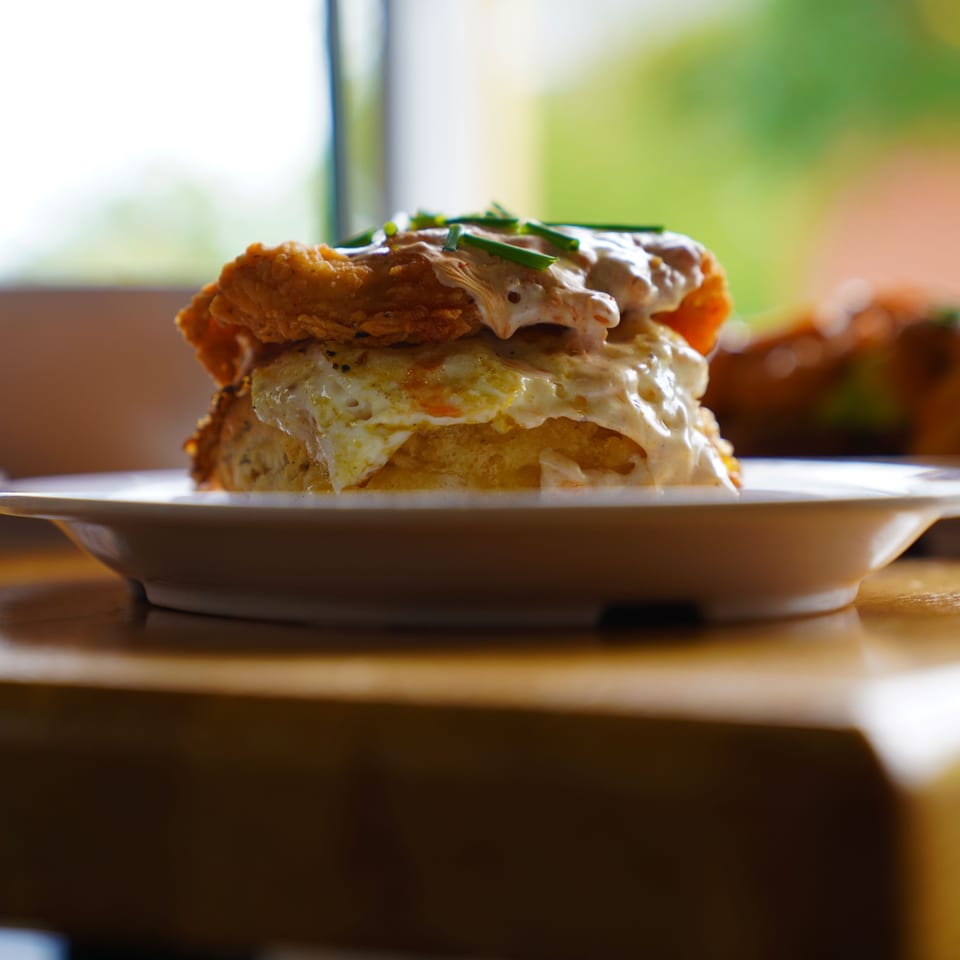 A close-up of The Real Milk & Honey's fried chicken and egg biscuit, drizzled with sauce and chives.