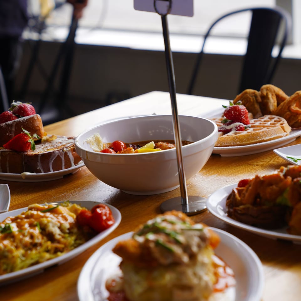 A table laden with various brunch dishes, including French toast, waffles, and savory entrees.