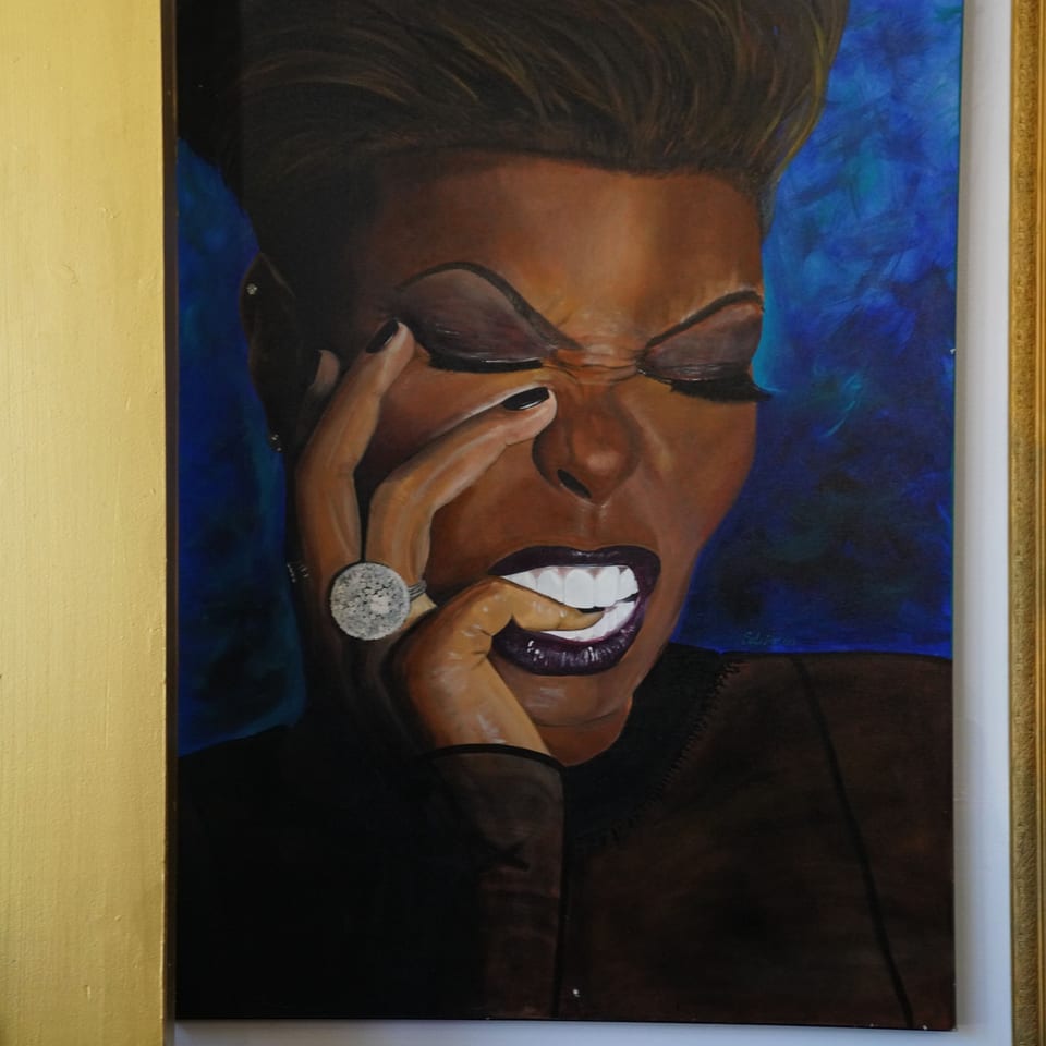 Painting of a woman with dark skin, closed eyes, and a hand to her face, biting her finger.