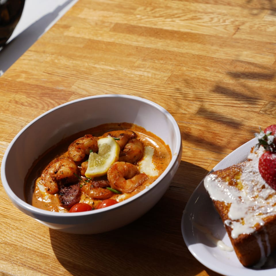 Shrimp and grits with lemon and cherry tomatoes, alongside French toast with strawberries.