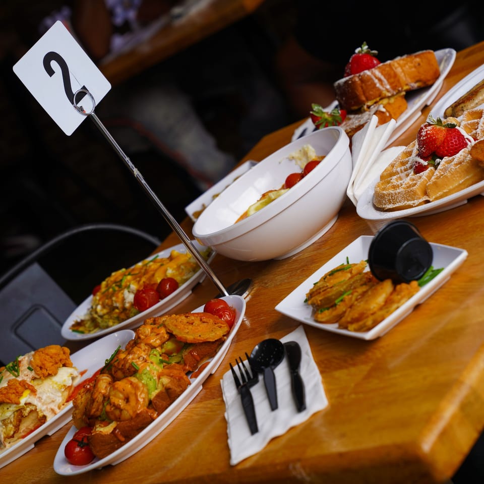 Table laden with various brunch dishes, including waffles, French toast, and savory items.